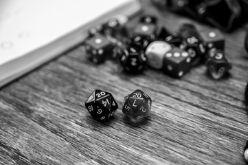 Multiple gaming dice on wooden table with 20 shown on a pair of d20