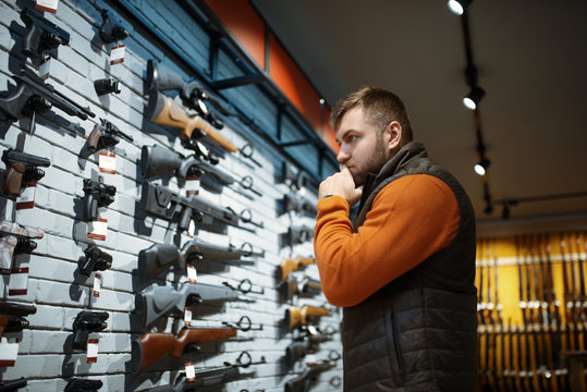 Man looking on handguns, showcase in gun shop