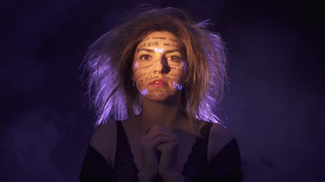 Girl in fog and Dramatic Purple light with written different language words on her face. Beautiful model with UV Fluorescent neon creative make-up. face close up