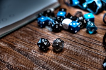 Multiple gaming dice on wooden table with 20 shown on a pair of d20