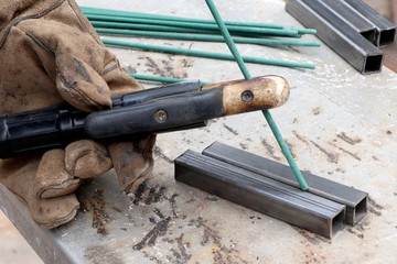 Worker welding metal thing. Tools for electro-gas welding