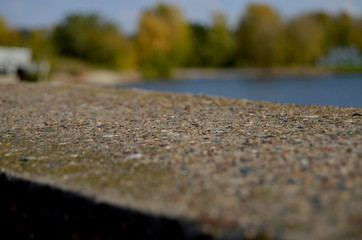 the embankment of the river close-up of the gray stone against the background of the river and trees