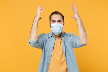 Irritated young man in sterile face mask posing isolated on yellow wall background studio portrait....