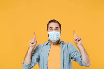 Young man in sterile face mask posing isolated on yellow background studio portrait. Epidemic...