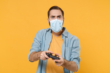 Shocked young man in sterile face mask posing isolated on yellow background studio portrait....