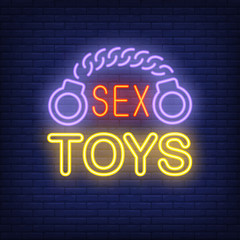 Handcuffs with Sex Toys lettering. Neon sign on brick background. Sex shop, electric sign, nightclub. Erotica concept. For topics like entertainment, love, business