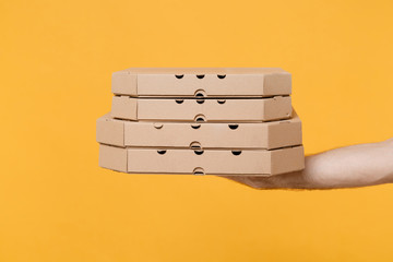 Close up cropped photo of male hold pizza in cardboard flatbox isolated on yellow background. Food delivery service from restaurant to home. Epidemic pandemic coronavirus 2019-ncov covid-19 flu virus.