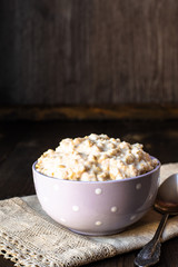 oatmeal porridge with milk for breakfast, in a bowl, wooden background