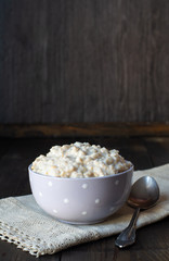 oatmeal porridge with milk for breakfast, in a bowl, wooden background