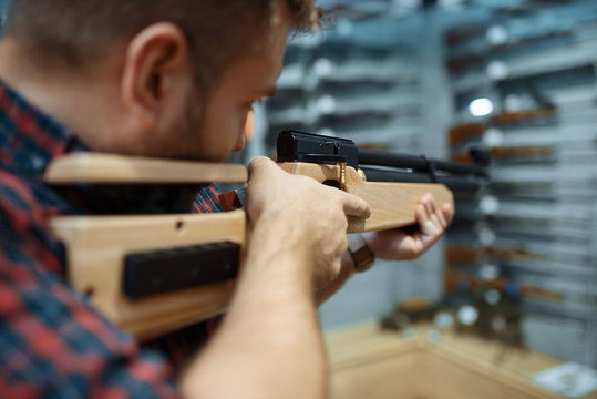 Male person with pneumatic rifle in gun shop