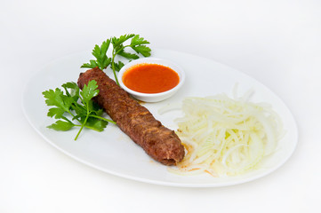 Grilled fishcakes with onions, parsley, tomato meat sauce on an oval white plate on a white plate