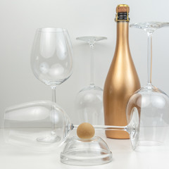 Creative composition with marzipan dessert, glass goblets and a golden bottle of champagne.