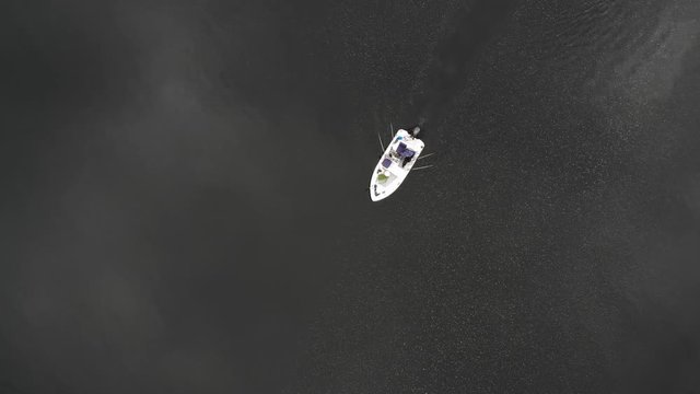 Motorboot mit Ausr&uuml;stung zum Angeln mit Schlepprouten f&auml;hrt auf stillem See bei Bew&ouml;lkung im Fr&uuml;hling