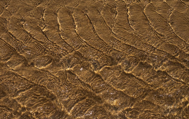 Waves and sand. The sun glare from the water on the sand