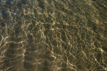 Waves and sand. The sun glare from the water on the sand