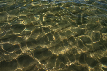 Waves and sand. The sun glare from the water on the sand