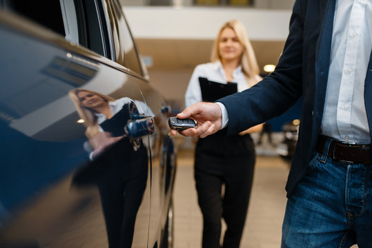 Man and saleswoman choosing auto in car dealership