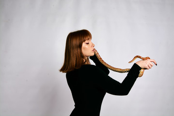 Beautiful woman in black bodywear and snake. Ginger model girl with fashion perfect make up.