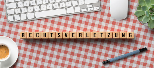 cubes with message RIGHT VIOLATION in German with computer equipment on tablecloth background