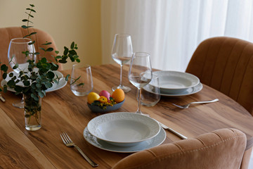 Easter table setting composition with traditional golden painted egg, beautiful tableware on natural dark wood textured table. Top view, copy space, close up, background.