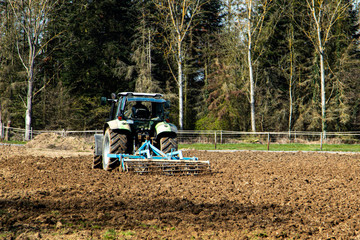 tractor on a field with a harrow to dig