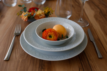 Easter table setting composition with traditional golden painted egg, beautiful tableware on natural dark wood textured table. Top view, copy space, close up, background.