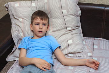 The child is measured temperature. A sick child with a thermometer under his arm lies on the bed. Virus. flu