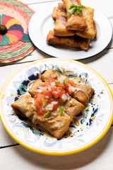 Mexican chimichanga with melted cheese and pico de gallo sauce on white background