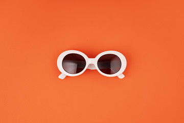 Stylish sunglasses over orange background. Summer fashion, party, summertime style, vacations concept. Minimal flat lay