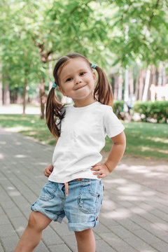 Cute smiling little girl 5 years old in white t-shirt in park