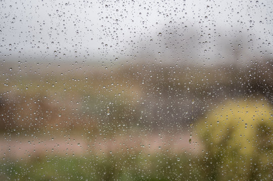 Regentropfen an der Fensterscheibe als melancholischer Hintergrund zum Thema Wetter und Depression
