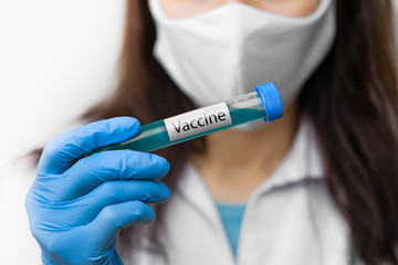 Test tube with vaccine against coronavirus, 2019-nCoV, SARS-nCov, COVID-19 in scientist hand wearing protective mask and blue gloves.