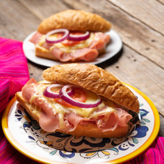 Mexican ham sandwich with melted cheese also called torta on wooden background