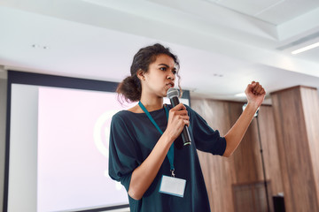 Focus on Success. Female speaker with microphone giving a powerful talk on corporate business...