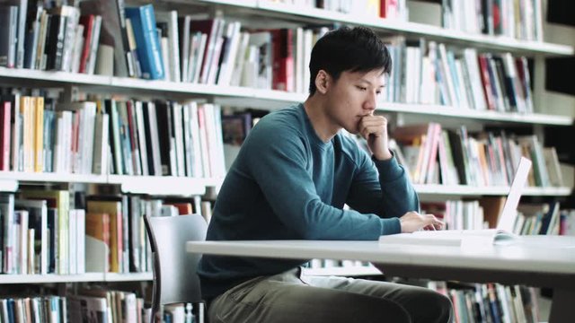 Asian Adult Male Student Reading In Library