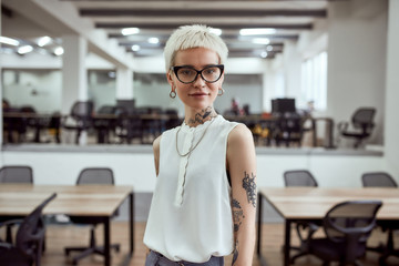 Modern businesswoman. Portrait of young beautiful blonde tattooed businesswoman in eyeglasses...