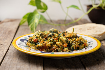 Mexican scrambled eggs with spinach on wooden background