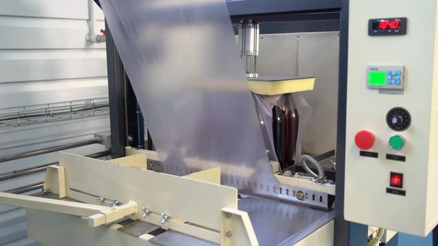 Box packaging of glass brown large bottles with beer, lemonade. Shrink machine.