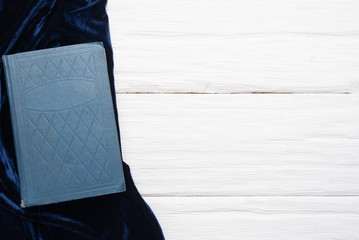 Blue book and blue velvet cloth on white flat lay background with copy space.