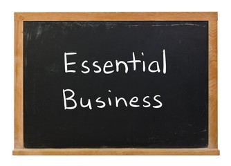 Fototapeta premium Essential Business written in white chalk on a black chalkboard isolated on white