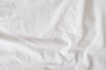 Background of white rumpled sheets. Bed linen with wrinkles in day light. Horizontal. Copy spase. Concept of rest, awakening, sleep, stay at home. For social media, blog