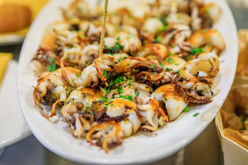 Traditional Italian street food in Venice - fried baby calamari on display on a plate at a stall