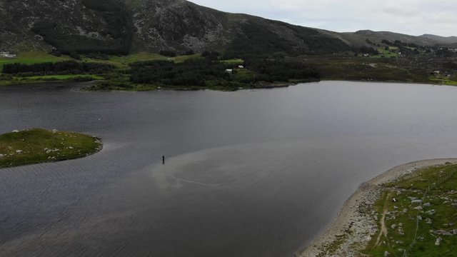 Angler mit Fliegenroute im See stehend aus Vogelperspektive bei Bew&ouml;lkung mit Bergen
