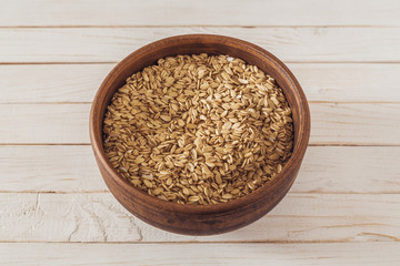 raw oatmeal in a brown clay plate on a white wooden boards