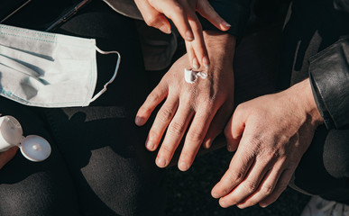 woman help a man lotion the hand, which is roughened due to disinfectant. - covid-19 corona crisis concept picture