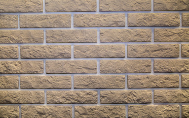 Background of beige artificial stone rectangular shape with a corrugated surface in the form of a wall of bricks. Backgrounds, textures, and design.