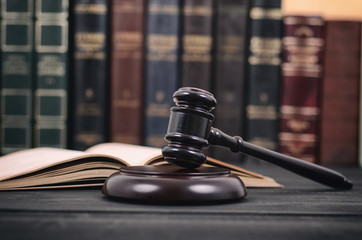 Judge Gavel and law book on a black wooden background, law library concept.