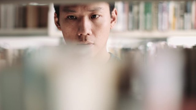 asian adult male student reading in library
