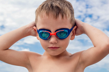 The boy is a swimmer. Sun, summer, vacation, joy. Purposeful, ready to dive boldly. Learning to swim in the sea with glasses. It is better to dive in glasses for swimming.