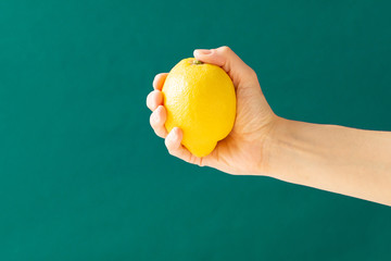 Hand holding lemon. Green background. Concept:, healthy living, eat local food, immune system. Creative banner. Copy space. Isolated.